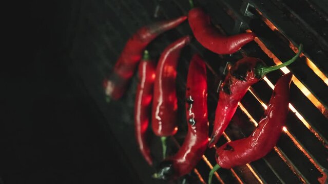 Red Pepper on the Grill With Fire. Vegetables on grill barbecue outdoors. Cooking roasted hot chilli peppers on barbecue gas grill. BBQ on Black Background, Vertical video, outdoors