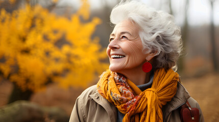 Portrait of an elderly happy smiling woman in autumn park, positive cheerful aged lady enjoying a...