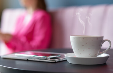 A refreshing cup of hot coffee in a cafe on the background of a freelancer girl