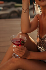 Young woman hands holding freshly squeezed strawberry lemonade of citrus fruits. Female with mason jar full of cold cocktail, lemon, orange, lime mint leaves