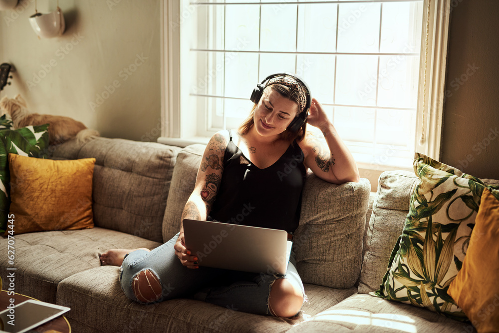 Wall mural sundays are for marathon movie streaming sessions. shot of a young woman using a laptop and headphon