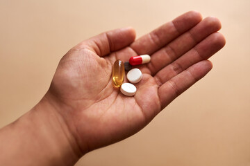 Some illnesses require a cocktail of pills. Studio shot of an unrecognisable woman holding a handful of pills against a brown background.