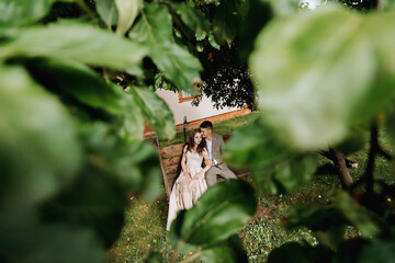portrait of a bride and groom in love on a swing from above through the leaves of a tree