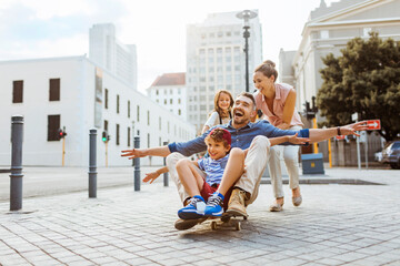Young family having fun with a skateboard downtown