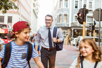 Young businesman father taking his kids to school in the downtown city