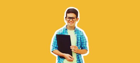 Portrait of happy smiling teenager boy in eyeglasses with folder or book on yellow background