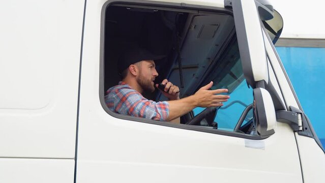 Semi Truck Driver Making Conversation with Other Truck Drivers Through CB Radio. Right Hand Drive Car