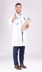Asian man, doctor and portrait with thumbs up for healthcare approval against a white studio background. Happy male person or medical expert smile with clipboard, like emoji or yes sign for success