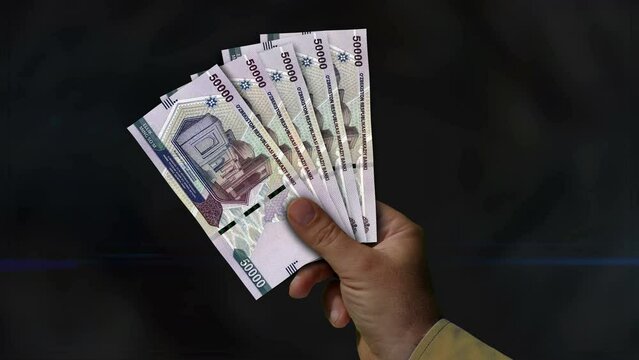 Uzbekistan Sum money holding. Fan of banknotes in hand. UZS paper cash. Concept of income, success, business, tax, economy and finance.