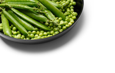 Fresh green peas in pods and peeled pea seeds in a round plate, isolated on white background.