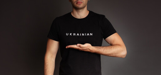 Close up studio photo of young man from Ukraine in black t-shirt with sign or slogan 