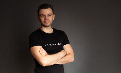 Close up studio photo of young man from Ukraine in black t-shirt with sign or slogan 