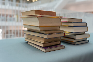 A stack of books lying on the table. A lot of books are on the table. A large stack of books are collected in one place.