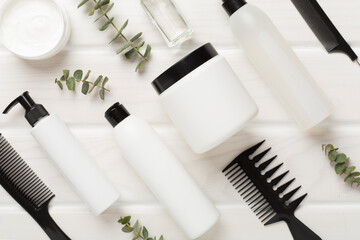 Professional hair care products with comb on wooden background, top view