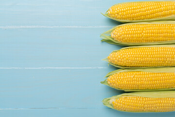Fresh corn on cobs on wooden background, top view