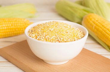 Corn groats with fresh cobs on wooden table