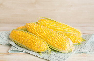 Fresh corn on cobs on wooden table