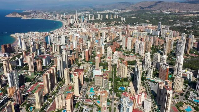 Aerial drone footage of the beautiful city of Benidorm in Spain in the summer time showing the Playa de Levante beach and the high rise apartments and hotels in the city in the summer time