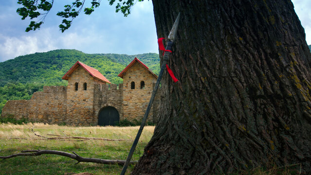 Roman fort and a spear leaning on an old tree in a summer day.