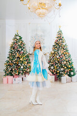 Snow Maiden in costume with short skirt and kokoshnik. room with christmas tree.