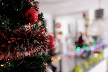 Close up focus on christmas tree decorated in red with modern office blurry in background. Ornate...