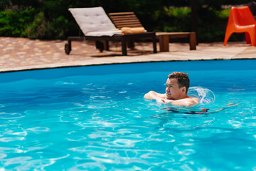 Naklejka premium Portrait of a cheerful middle-aged man in the pool with inflatable lifebuoy.