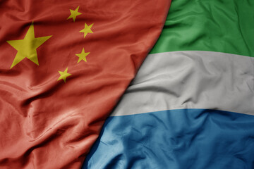 big waving national colorful flag of china and national flag of sierra leone .