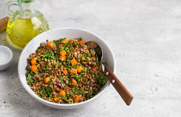 Buckwheat with vegetables and kale on a gray textured background, top view. Delicious healthy vegan food