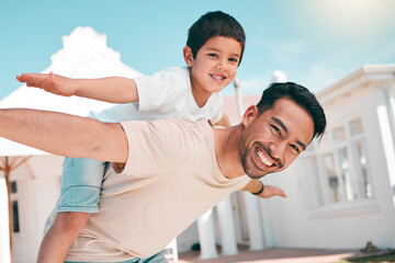 Happy, airplane and portrait of a father with his child in the outdoor garden at their family home. Playful, smile and young dad carrying his boy kid on his back while bonding and playing together.