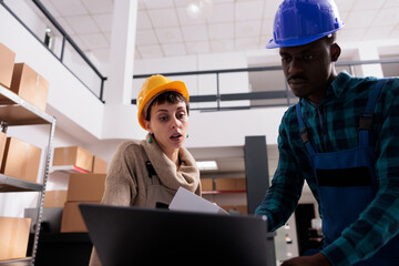 Ecommerce storehouse operatives checking online order for parcel preparation. African american and...