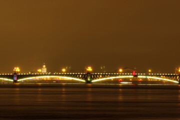 Night view of the bridge over the river illuminated by light, blurry. Night shot through the fog.