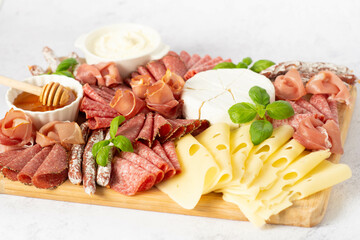 Brie cheese, blue cheese, salami, prosciutto on a wooden board.