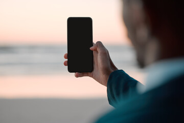 Businessman, hands and phone screen on beach for communication, advertising or outdoor networking. Closeup of man with mobile smartphone app display mockup by ocean coast for business trip or travel