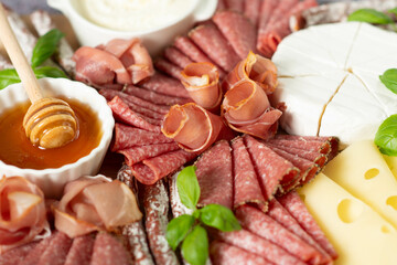 Brie cheese, blue cheese, salami, prosciutto on a wooden board.