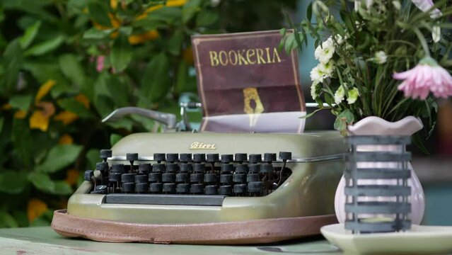 Mechanical military Bisel semi-portable typewriter. Pot of pink flowers. Restaurant advertising vintage accessory. Eye catcher. Props to attract customers. Cozy resort. Rovinj, Croatia - July 7, 2023