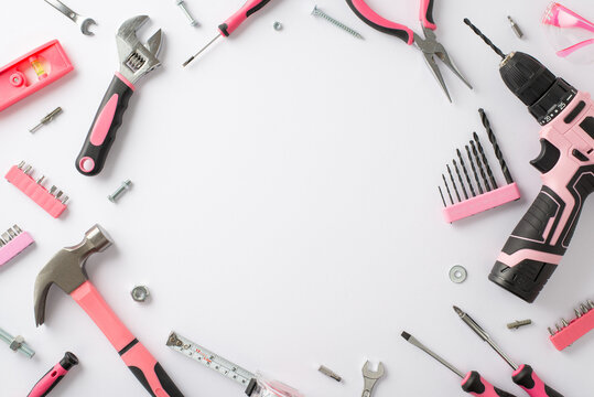 Embracing the significance of women's contributions on Labor Day. Overhead image showcasing pink construction tools on a white isolated background, with empty circle for text or ads