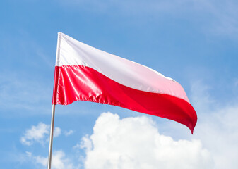 The national flag of Poland in the daytime on the background of the blue sky