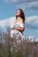 Pregnant young woman enjoying the sunset standing in a lavender field.