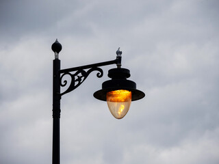 Old style lantern lamp in a street on a metal fancy pole with modern LED bulb. City street...