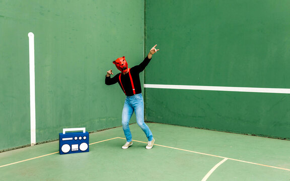 Man wearing animal mask dancing near boombox