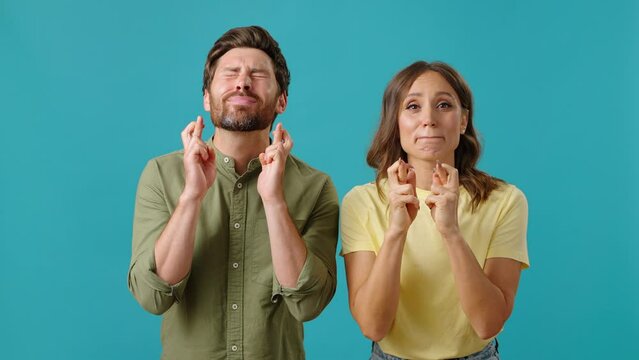 Man and woman ask crossing fingers and making prayer gesture