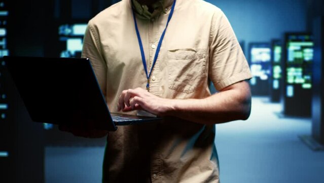 Close up of technician walking between operational server clusters in high performance computing data center, ensuring optimal operations. Admin monitoring energy consumption across systems