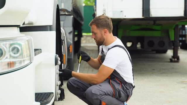 Truck driver using socket wrench while changing tire on car service