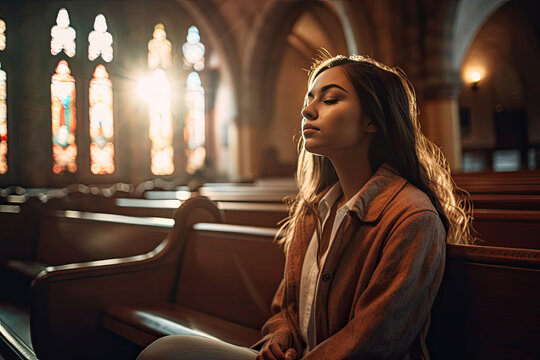 a young woman praying in church. Conceptual image for Christian faith, religion and prayer.