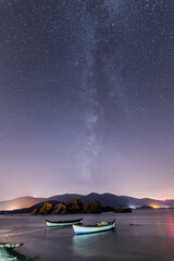 A view of the stars of the Milky Way with a mountain top in the foreground. Night sky nature summer...