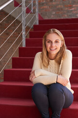 Campus life. Portrait of a university student sitting on a staircase at campus.