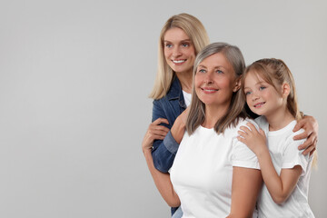 Obraz premium Three generations. Happy grandmother, her daughter and granddaughter on light gray background, space for text