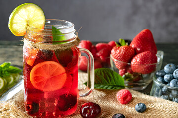 Refreshing berry cocktail with ice and lemon. Raspberry, lime, strawberry, blueberry, and leaves mint. Berry mojito close-up.