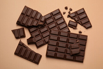 Pieces of delicious dark chocolate bars on beige background, flat lay