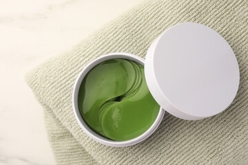 Jar of under eye patches and towel on white background, top view. Care products